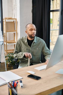 İş kıyafeti giymiş, miastenya gravis 'i olan engelli bir Afrikalı Amerikalı laptopun önünde oturmuş şirket kültürü ve verimliliği üzerine bir proje üzerinde çalışıyor..