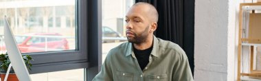 Kel, özürlü, miastenya gravis 'i olan Afro-Amerikan bir adam derin düşüncelere dalmış, derin düşüncelere dalmış bir pencerenin önünde duruyor..