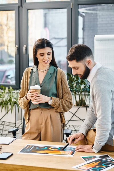 A man and a woman reminiscing over memories captured in photos spread out on a table in an office setting.