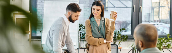A man and woman engrossed in a cell phone, collaborating on a project in a corporate office setting.