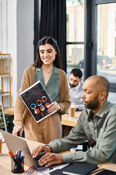 Мужчина и женщина участвуют в деловой встрече, внимательно работая над проектом вместе на ноутбуке в корпоративном офисе.