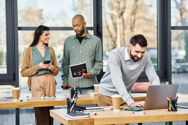 İki erkek ve bir kadın bir projede işbirliği yapıyorlar. Modern bir ofis ortamında dizüstü bilgisayarla çok meşguller..