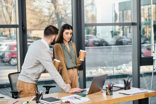 Bir erkek ve bir kadın, bir ofis ortamında dizüstü bilgisayarın başında bir iş projesine girişiyor..