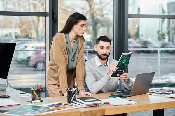 Bir erkek ve bir kadın çizelgelere bakarken, bir ofis ortamında bir proje üzerinde çalışırken tartışırlar..