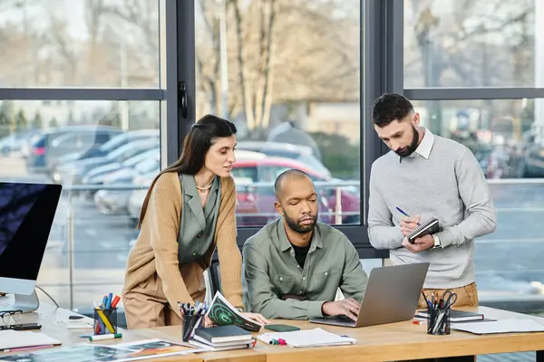 Üç iş adamı bir şirket ortamında dizüstü bilgisayarın etrafında proje tartışması yapıyor.