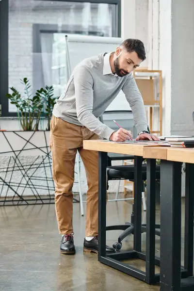 彼のノートパソコンに焦点を当て 忙しいオフィスの机に立って 企業文化に不可欠なプロジェクトに取り組む男 — ストック写真