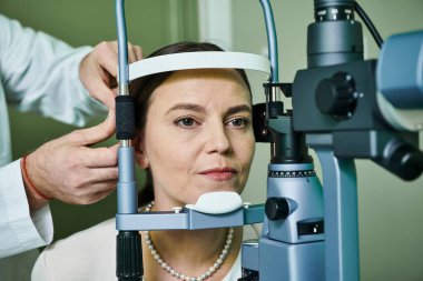 Profesyonel ortamda bir kadının gözünü muayene eden bir doktor..