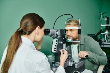 Appealing doctor examining a mans eye in a professional setting. clipart