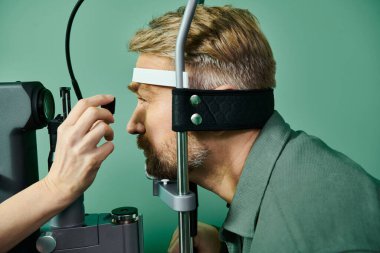 Kendini adamış doktor, doktorun muayenehanesinde lazer görme düzeltmesi için adamın gözlerini mikroskopla inceliyor..