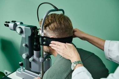Doctor with wristwatch examines mans eyes in a doctors office for laser vision correction. clipart