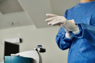 Lazer görme düzeltme kliniğinde mavi elbiseli ve beyaz eldivenli bir kadın..