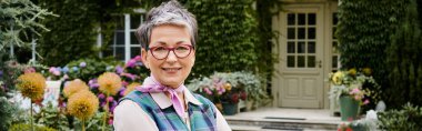 refined mature joyous woman with short hair smiling at camera near her house in England, banner clipart