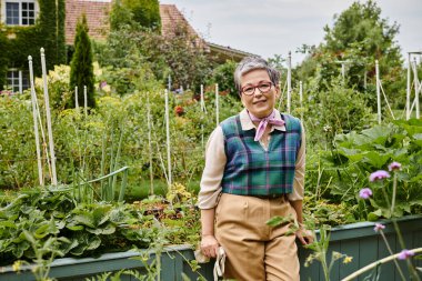 İngiltere 'deki evinin yakınındaki kameraya gülümseyen kısa saçlı ve gözlüklü zarif olgun kadın.