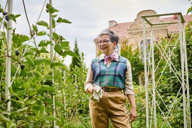 sofistike, neşeli, olgun, kısa saçlı, şık giyinmiş, bitkileriyle ilgilenen bir kadın.