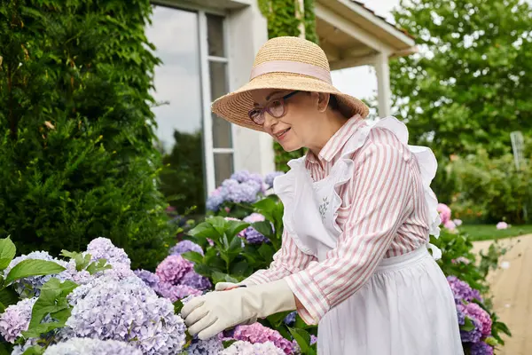 Güzel görünümlü, önlüklü, gözlüklü olgun bir kadın güzel ortancasına bakıyor.