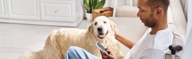 Miyastenia gravis 'i olan özürlü Afrikalı Amerikalı bir adam kanepeye oturmuş, sadık Labrador köpeğini şefkatle okşuyor..