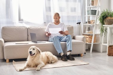 A disabled African American man with myasthenia gravis sits on a couch next to his Labrador dog at home, emphasizing diversity and inclusion. clipart