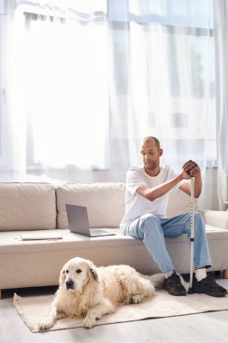 Engelli bir Afrikalı Amerikalı, sadık Labrador köpeğinin yanında rahat bir kanepede rahatlar, çeşitlilik ve kapsamı kucaklar..