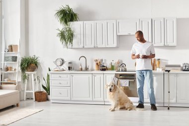 African American man with myasthenia gravis stands in kitchen with Labrador, showcasing diversity and inclusion. clipart