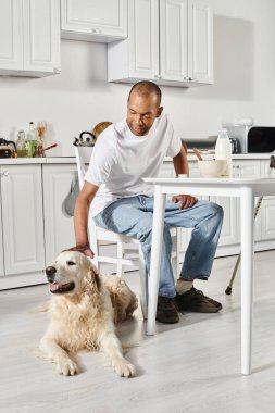 Engelli bir Afrikalı Amerikalı adam Labrador köpeğiyle aynı masada oturuyor ve birlikte huzurlu bir anın tadını çıkarıyor..