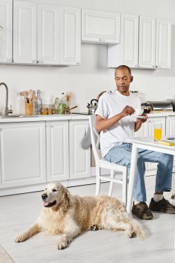 Sadık Labrador köpeğiyle mutfak masasında oturan engelli bir Afrikalı Amerikalı..