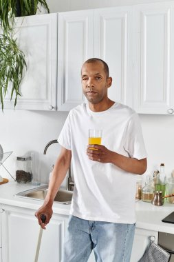 An African American man with myasthenia gravis syndrome stands in a kitchen holding a glass of orange juice. clipart