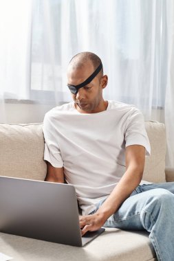 Kanepede dizüstü bilgisayar kullanan miastenya gravis sendromu olan Afrikalı Amerikalı bir adam..