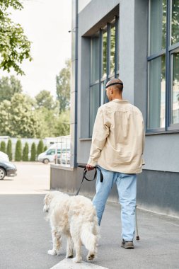 A disabled African American man with myasthenia gravis syndrome is walking a white Labrador dog down a street in a display of diversity and inclusion. clipart