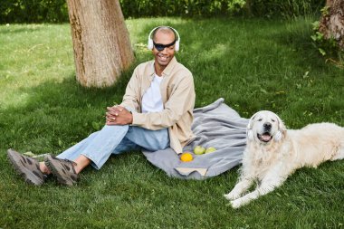 A man with myasthenia gravis syndrome sits on a blanket next to his loyal Labrador dog, lost in thought. clipart