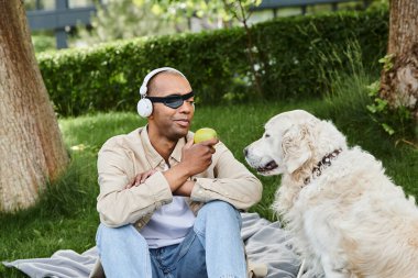Myastthenia Gravis 'i olan bir adam beyaz bir Labrador köpeğinin yanında bir battaniyenin üzerinde oturuyor. Huzurlu bir çeşitlilik ve kapsama anında..