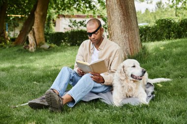 Miyastenia gravis 'i olan Afro-Amerikalı bir adam çimenlerde oturmuş kitap okuyor ve sadık bir Labrador köpeği onun yanında oturuyor..