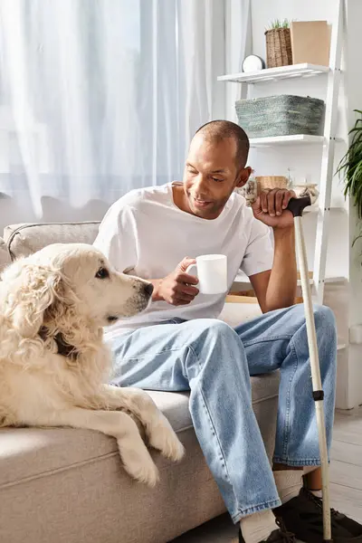 stock image An African American man with myasthenia gravis sits next to his loyal Labrador dog on a comfy couch, enjoying a moment of peace and companionship.