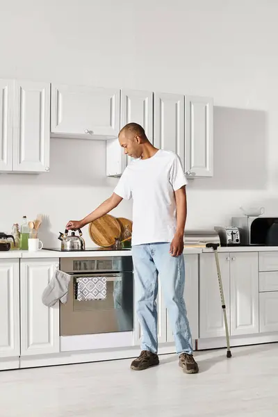 stock image An African American man with myasthenia gravis stands in a kitchen looking thoughtful next to a sink.