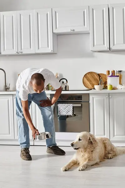 アフリカ系アメリカ人男性と彼の忠実なラブラドール犬は 暖かく居心地の良いキッチンで一緒に時間を過ごしています — ストック写真