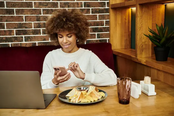 一个现代的非洲裔美国女人坐在咖啡店的桌子旁 专心致志地拿着手机 — 图库照片