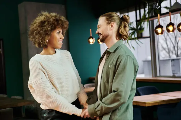 stock image A stylish African American woman and a man stand together in a modern cafe, exuding confidence and connection.