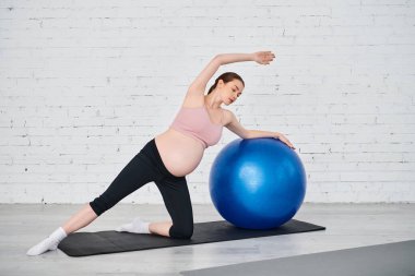 Hamile bir kadın doğum öncesi dersler sırasında yoga topunda huzur içinde yoga yapıyor..
