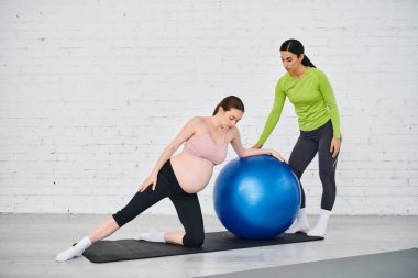 Hamile bir kadın ve koçu, ebeveyn kursları sırasında yoga topunda egzersiz yapıyor, fitness ve sağlığı destekliyor..