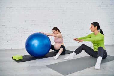 İki kadın yoga minderlerine güzelce oturur, paylaşılan deneyimlerle birbirlerine bağlanırken farkındalık ve güç pratiği yaparlar..