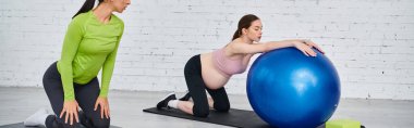 İki kadın, biri hamile, ebeveyn kursu sırasında koçun rehberliğiyle bir spor salonunda denge topları üzerinde egzersiz yapıyorlar..
