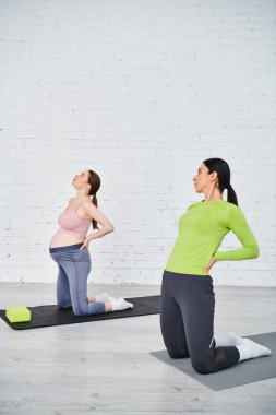 Hamile kadın, hocasının rehberliğinde sakin bir stüdyoda yoga yapıyor..