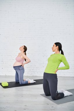 pregnant woman gracefully practice yoga in a serene studio under the guidance of her instructor. clipart