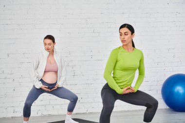 Müstakbel anne doğum öncesi egzersiz sırasında kırsal tuğla duvarın önünde nazikçe yoga yapıyor..