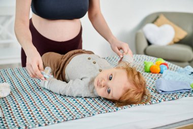 Bir bebek, bir yatakta genç bir kadının yanında huzur içinde yatar, anne ve çocuk arasındaki huzurlu ve besleyici anı yakalar..