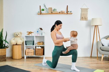 Genç ve güzel bir anne bebeğiyle yoga yapıyor. Bir koçun rehberliğinde bakım evi ortamında..