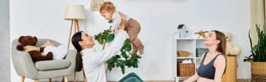 Genç bir anne, bir aile kursunda koçun desteğiyle omuzlarında bir çocukla yerde oturuyor..