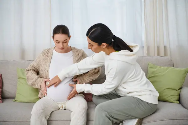 妊娠中の女性は 両親のコースの間に彼女のトレーナーの隣のソファに座っています — ストック写真