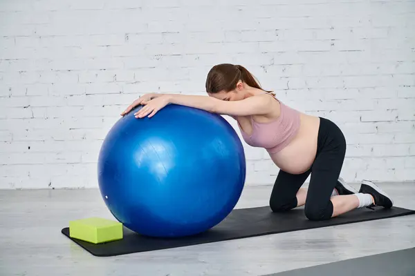 在一个家长课程中 一名孕妇在教练的指导下 正在用一个运动球来锻炼自己的身体 — 图库照片