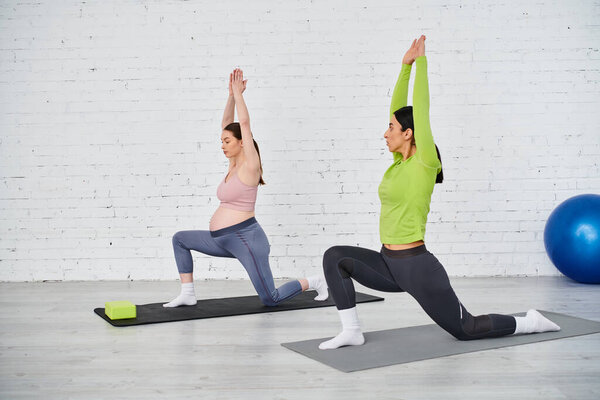 A pregnant woman gracefully practices yoga with her instructor during a parent course session on a colorful mat.