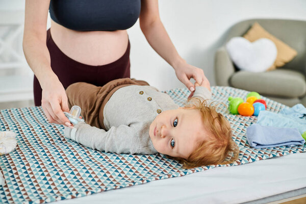 A baby peacefully lays beside a young woman on a bed, capturing a serene and nurturing moment between mother and child.